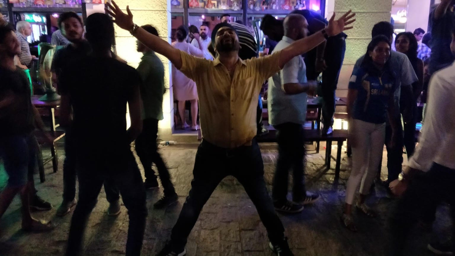 A man throwing his arms wide in celebration at an evening party