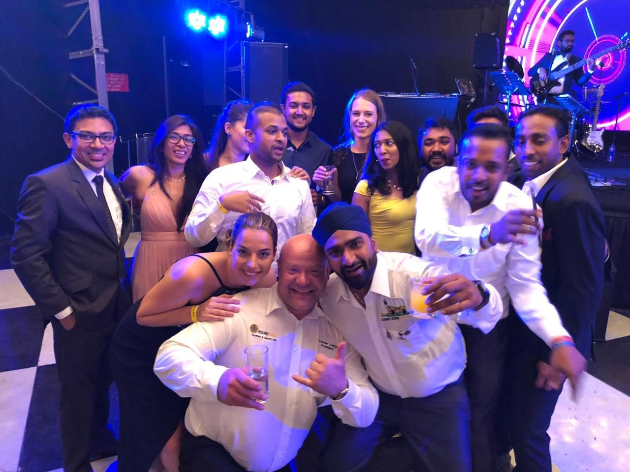 A big group of friends smiling together on a lit-up dance floor